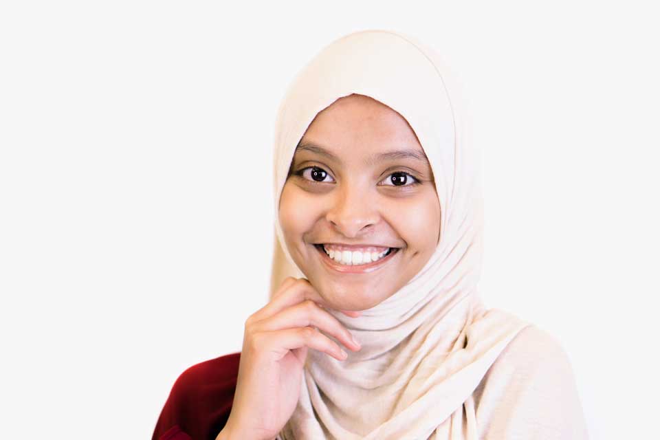 Woman smiling at camera wearing a cream colored burka